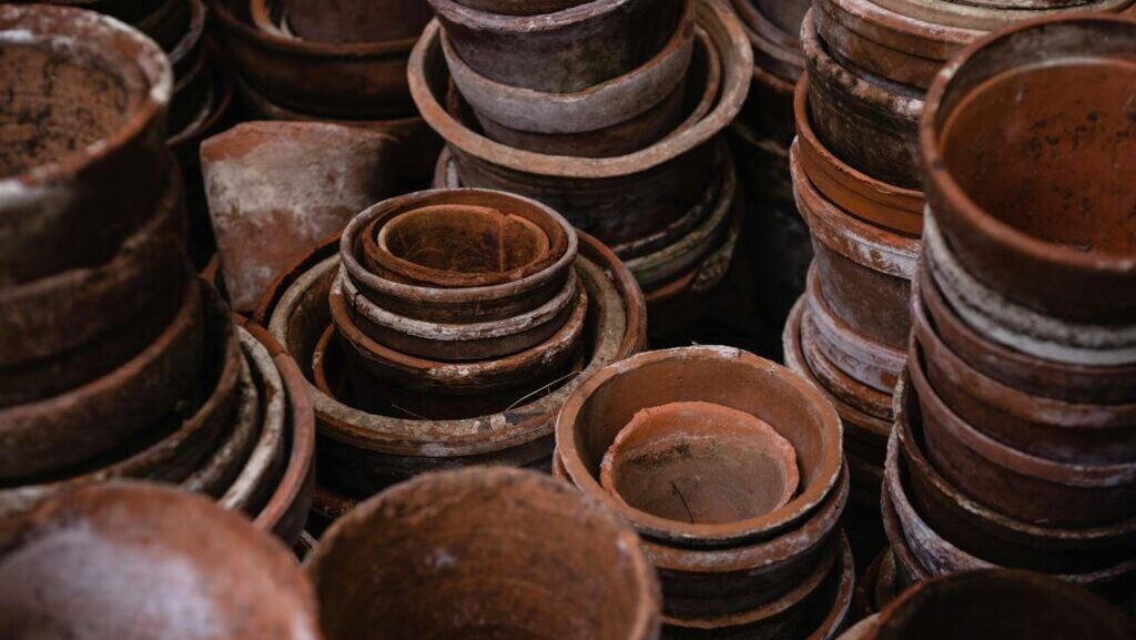 A collection of stacked earthenware pots showcasing rustic craftsmanship and texture, Czym się różni styl wabi sabi od japandi, wabi sabi